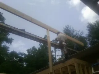 Carpenter setting a ridge beam over a new addition frame — Ice Dam Removal by Roofing Brothers in Summerland
