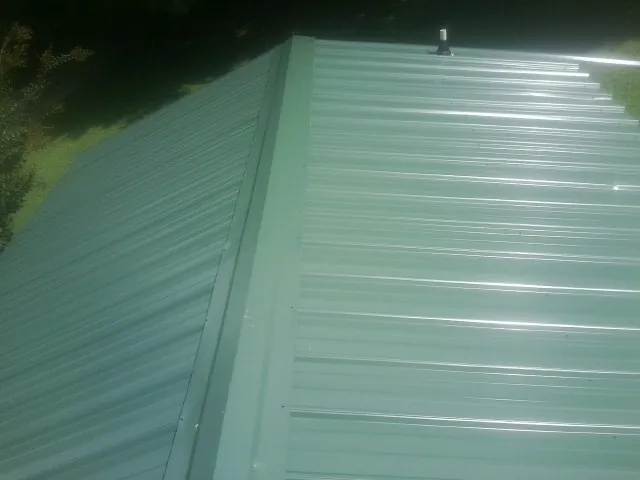 New green metal panels meeting at the ridge of a roof — Flat Roof Repair work by our crew in Summerland