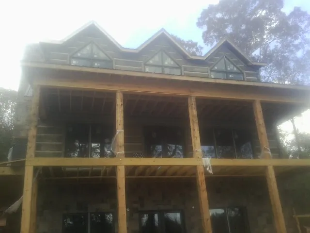 Dormers and porch framing on a large log home under construction — Roof Coating work by our crew in Summerland