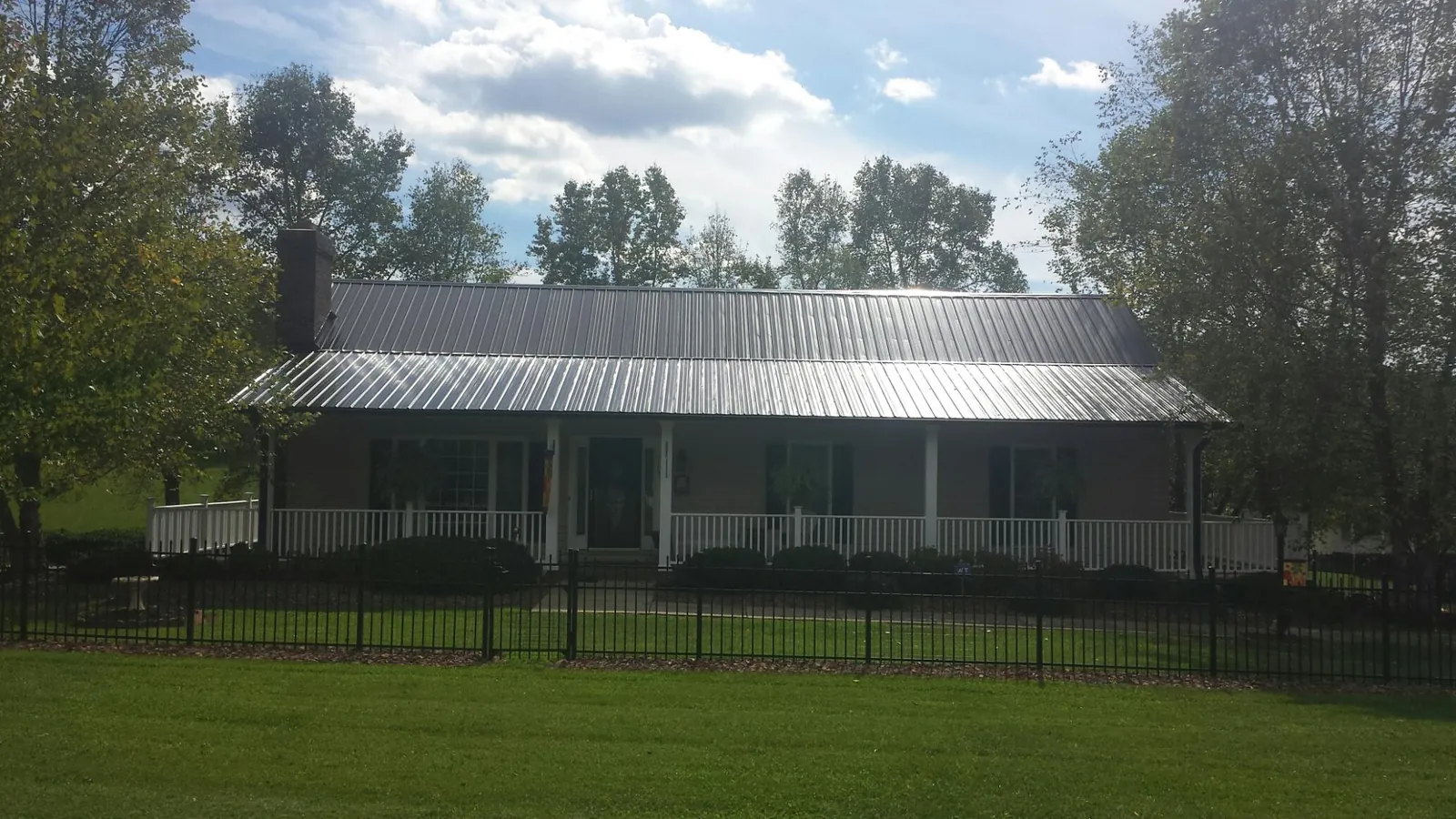 Gray metal roof on a brick ranch with a full width front porch — Gutter Guard Installation work by our crew in Summerland