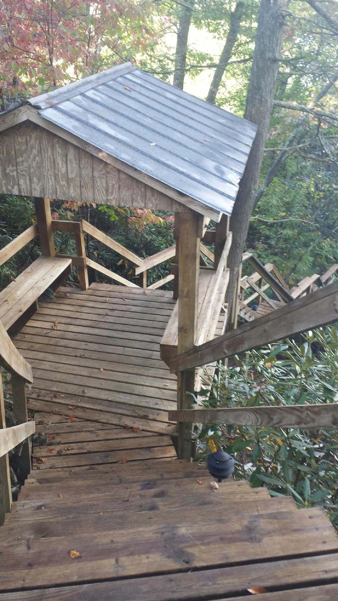 Metal roofed shelter over wooden steps on a wooded walkway — Skylight Repair & Installation work by our crew in Summerland