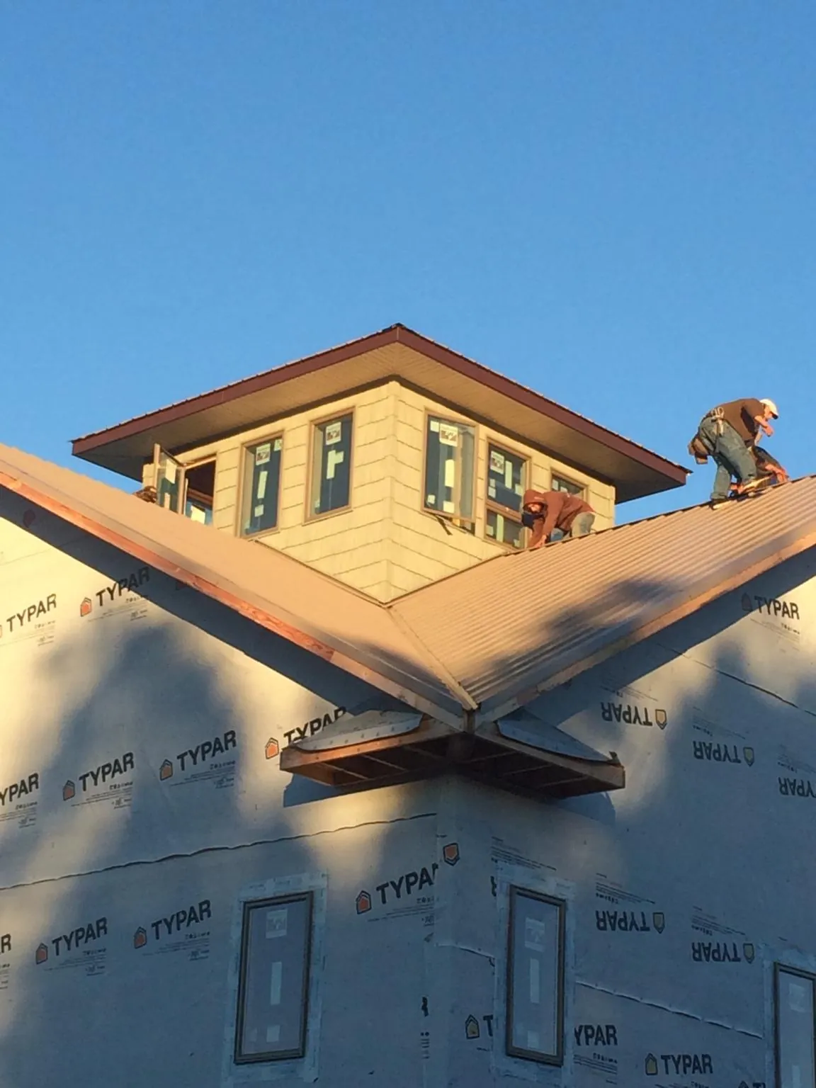 Roofers working around a rooftop cupola on a new metal roof at sunset — Roof Waterproofing in Summerland by Roofing Brothers